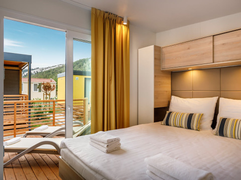 Camera da letto moderna al Lopar Garden Home con accesso al balcone e vista sul paesaggio naturale.