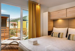Dormitorio moderno en Lopar Garden Home con acceso al balcón y vistas a la naturaleza desde la ventana.