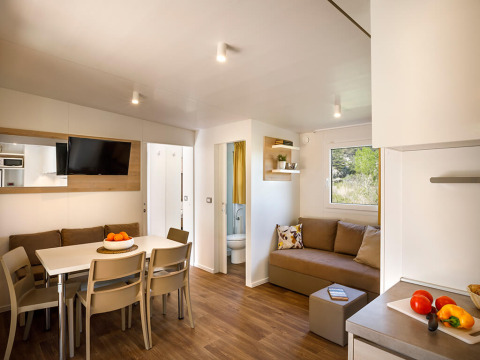 Soggiorno moderno al Lopar Garden Home di Valamar Camping San Marino, Croazia, con tavolo da pranzo e divano.