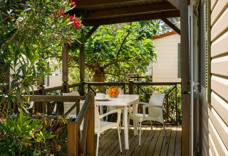 Überdachte Terrasse mit weißen Gartenmöbeln im Grünen, fotografiert im Valamar Camping San Marino, Kroatien.