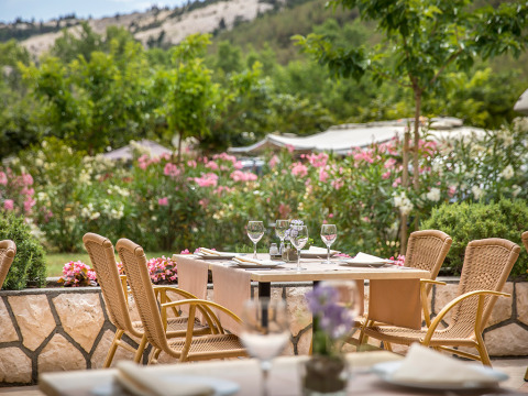 Zona de comedor al aire libre en Valamar Camping San Marino, Croacia, rodeada de flores y vegetación.