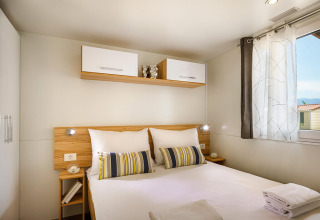 Dormitorio moderno en San Marino Home de Valamar Camping San Marino, Croacia, con cama doble y ventana soleada.