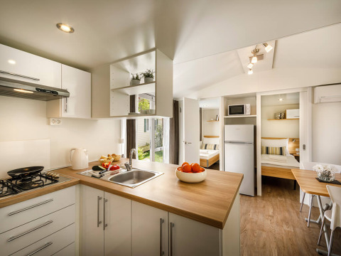 Cuisine moderne avec plan de travail en bois et vue sur les chambres du San Marino Home, Valamar Camping San Marino.
