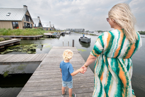 Moeder en kind wandelen hand in hand op een steiger bij het Oesterdam Resort in Zeeland, Nederland.