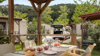Mesa exterior preparada para desayuno bajo porche cubierto en San Marino Home lodge con vistas verdes.