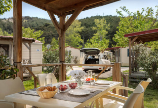 Table extérieure dressée pour le petit-déjeuner sur terrasse couverte au lodge San Marino Home, vue nature.