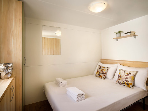 Knusse slaapkamer in San Marino Home bij Valamar Camping San Marino, Kroatië, met tweepersoonsbed en eenvoudig interieur.