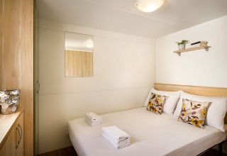 Acogedor dormitorio en San Marino Home en Valamar Camping San Marino, Croacia, con cama doble y decoración sencilla.
