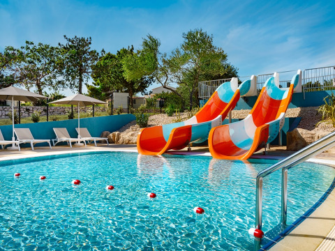 Piscina al aire libre con toboganes de agua coloridos y tumbonas en Valamar Camping Padova, Croacia.