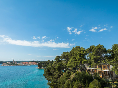 Vista sul mare blu, pini e case vacanza al Valamar Camping Padova, Primorje-Gorski Kotar, Croazia.