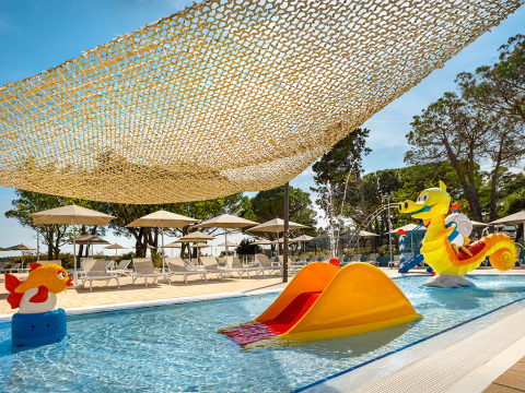Kinderpool mit Rutsche, Sonnenschirmen und Seepferdchenfigur im Ferienpark Valamar Camping Padova, Kroatien.
