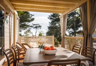 Terrazza coperta al lodge Marine Home con tavolo, sedie, lettini e una ciotola di arance sul tavolo.