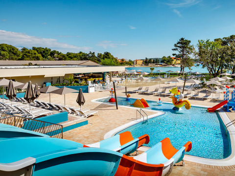 Outdoor swimming pool with water slides and sun loungers at Valamar Camping Padova, Croatia, near the sea.