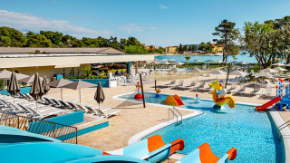 Outdoor swimming pool with water slides and sun loungers at Valamar Camping Padova, Croatia, near the sea.