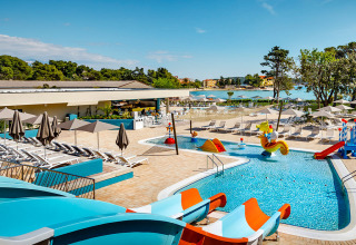 Buitenzwembad met glijbanen en ligstoelen bij Valamar Camping Padova, Kroatië, vlak bij de zee.