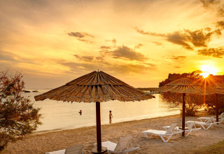 Strand med liggestole og parasoller ved solnedgang i nærheden af Banjol, Primorje-Gorski Kotar, Kroatien.
