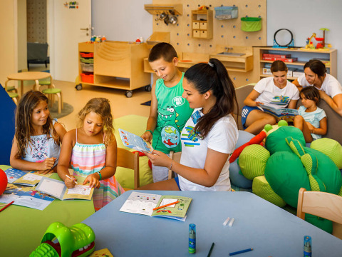 Kinder und Betreuer lesen und malen gemeinsam in einem farbenfrohen Spielzimmer im Valamar Camping Padova.