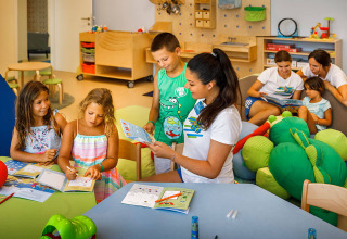 Niños y adultos participan en actividades educativas en una sala de juegos colorida en Valamar Camping Padova, Croacia.
