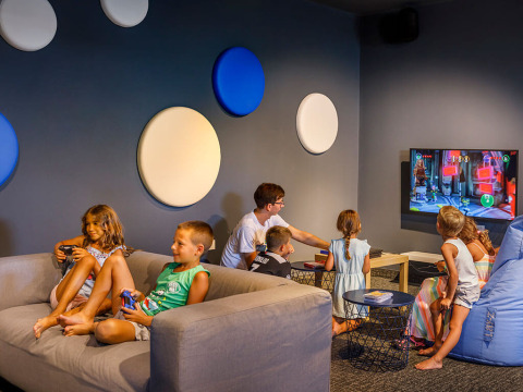 Kinderen spelen videogames in een kleurrijke speelkamer bij Valamar Camping Padova, Kroatië.