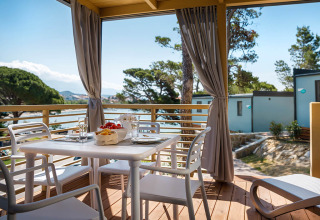 Terras met eettafel, stoelen en uitzicht op zee bij Valamar Camping Padova, Primorje-Gorski Kotar, Kroatië.