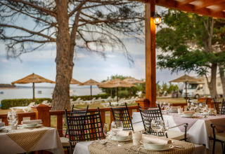 Zona pranzo all’aperto al Valamar Camping Padova con vista sulla spiaggia e ombrelloni in Croazia.