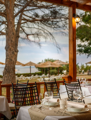 Outdoor dining area at Valamar Camping Padova overlooking the beach and parasols in Primorje-Gorski Kotar.