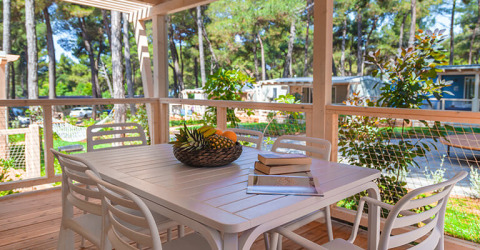 Udendørs terrasse med hvidt bord, stole, frugtskål og bøger på Valamar Camping Padova i Kroatien.