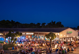 Serata vivace al Valamar Camping Padova in Croazia, con ospiti che socializzano all’aperto ai tavoli.
