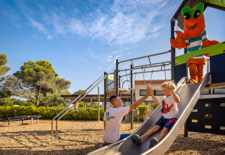 Niño se desliza en el tobogán y choca la mano con un adulto en Valamar Camping Padova, Croacia.