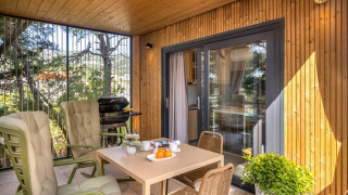 Terraza techada en Hilltop Green Chalet con sillas cómodas, mesa de comedor, plantas y barbacoa.