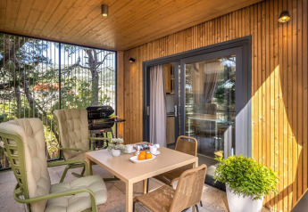 Udendørs terrasse ved Hilltop Green Chalet med hyggelige stole, spisebord, planter og grill.