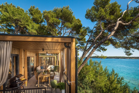 Udsigt fra Hilltop Green Home Spectacular seaview-lodge med træterrasse, havudsigt og grønne træer.