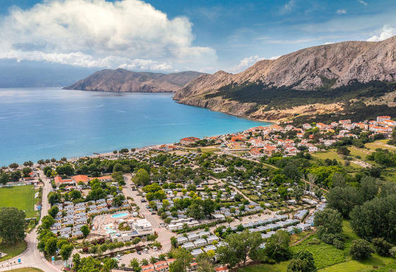 Vista aerea di Valamar Camping Baška, villaggio vacanze sulla costa di Primorje-Gorski Kotar, Croazia, con montagne.