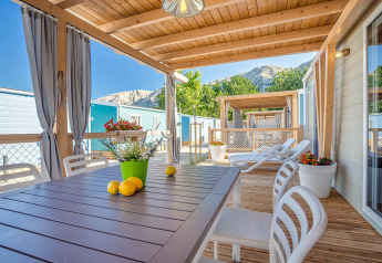 Terrazza esterna del Marena Home al Valamar Camping Baška, Croazia, con sedie, tavolo e vista montagna.