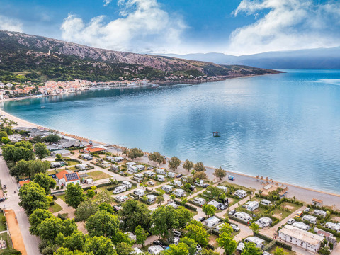 Aerial view of a seaside campsite near Baška, with clear water and mountains in Primorje-Gorski Kotar, Croatia.
