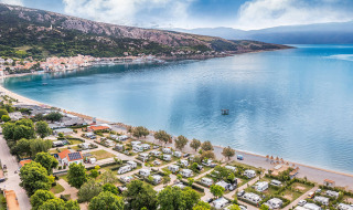 Luftaufnahme von Wohnwagen und Strand nahe Baška, mit Bergen im Hintergrund in Primorje-Gorski Kotar, Kroatien.