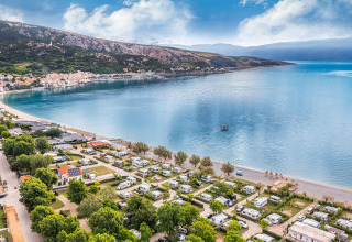 Vista aérea de un camping junto al mar cerca de Baška, rodeado de montañas en Primorje-Gorski Kotar, Croacia.