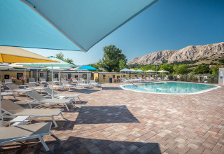 Poolbereich mit Liegestühlen und bunten Sonnenschirmen im Valamar Camping Baška, Primorje-Gorski Kotar, Kroatien.