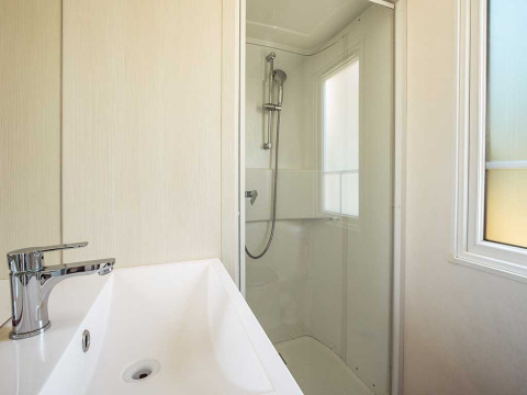 Salle de bain moderne avec lavabo blanc, robinet chromé et douche au Brioni Superior Home Seaside, Camping Brioni, Croatie.