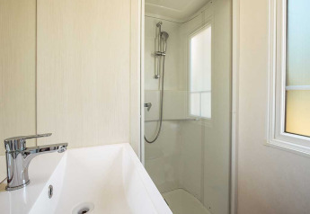 Salle de bain moderne avec lavabo blanc, robinet chromé et douche au Brioni Superior Home Seaside, Camping Brioni, Croatie.