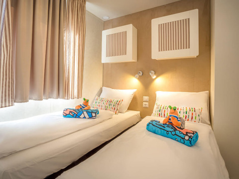 Moderne slaapkamer met twee eenpersoonsbedden, kleurrijke kussens en kinderspeelgoed bij Marena Home, Kroatië.