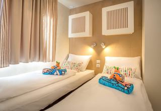 Moderne slaapkamer met twee enkele bedden, gekleurde kussens en speelgoed in Marena Home, Kroatië.