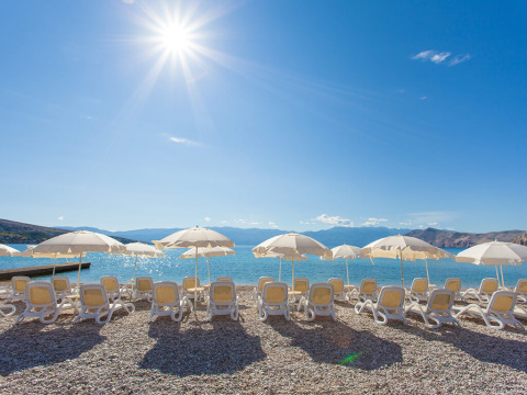 Sun loungers and umbrellas on the beach at Valamar Camping Baška in Primorje-Gorski Kotar County, Croatia.
