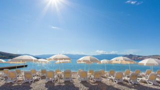 Sonnenliegen und Sonnenschirme am Strand von Valamar Camping Baška, Primorje-Gorski Kotar, Kroatien.