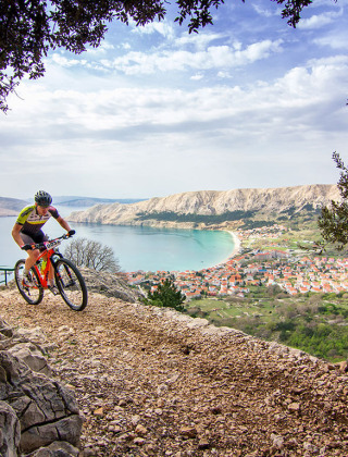 Mountainbiker auf felsigem Pfad mit Blick auf Baška und die Küste in Primorje-Gorski Kotar, Kroatien.