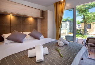 Modern lodge Vela Bay Home at Valamar Camping Baška in Croatia, featuring a comfy bed and garden terrace view.