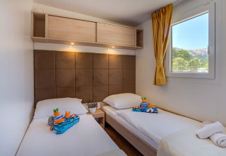 Moderne lodgekamer in Vela Bay Home, Kroatië met twee bedden, speelgoed en een raam met uitzicht.