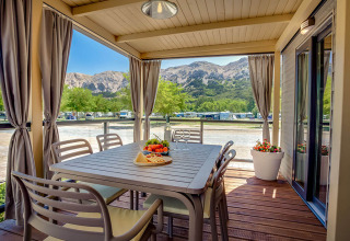 Outdoor dining area at Vela Bay Home lodge overlooking mountains at Valamar Camping Baška in Croatia.