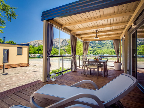 Overdekt terras van Vela Bay Home op Valamar Camping Baška in Kroatië met stoelen en uitzicht op bergen.