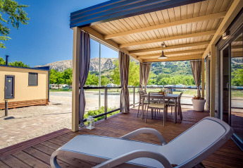Terrazza coperta della Vela Bay Home al Valamar Camping Baška in Croazia, con sedie e vista sulle montagne.